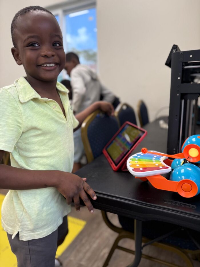 Boy smiling at Roboclub with tablet and robot