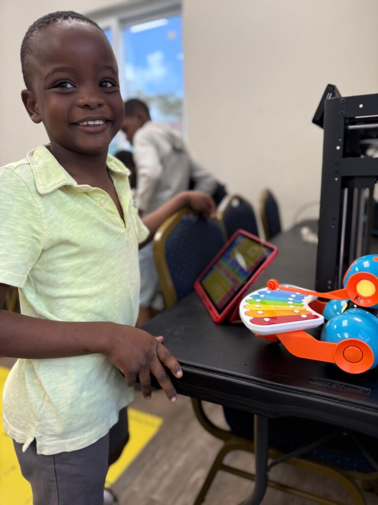Boy smiling at Roboclub with tablet and robot